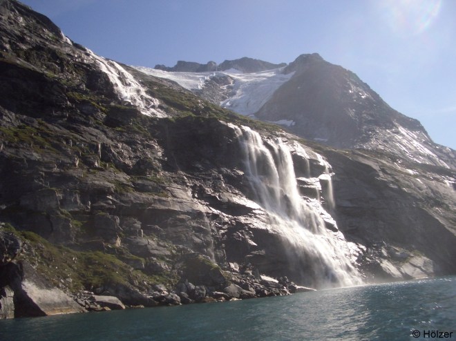 Das Schmelzwasser des Gletschers stürzt in einem Wasserfall ins Meer.
